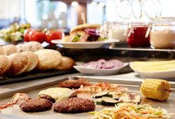 Burger Patties und Gemüse auf der Grillplatte