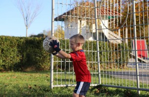 Kind hält Fußball in den Händen vor Tor