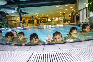 Kinder im Pool halten sich am Beckenrand fest